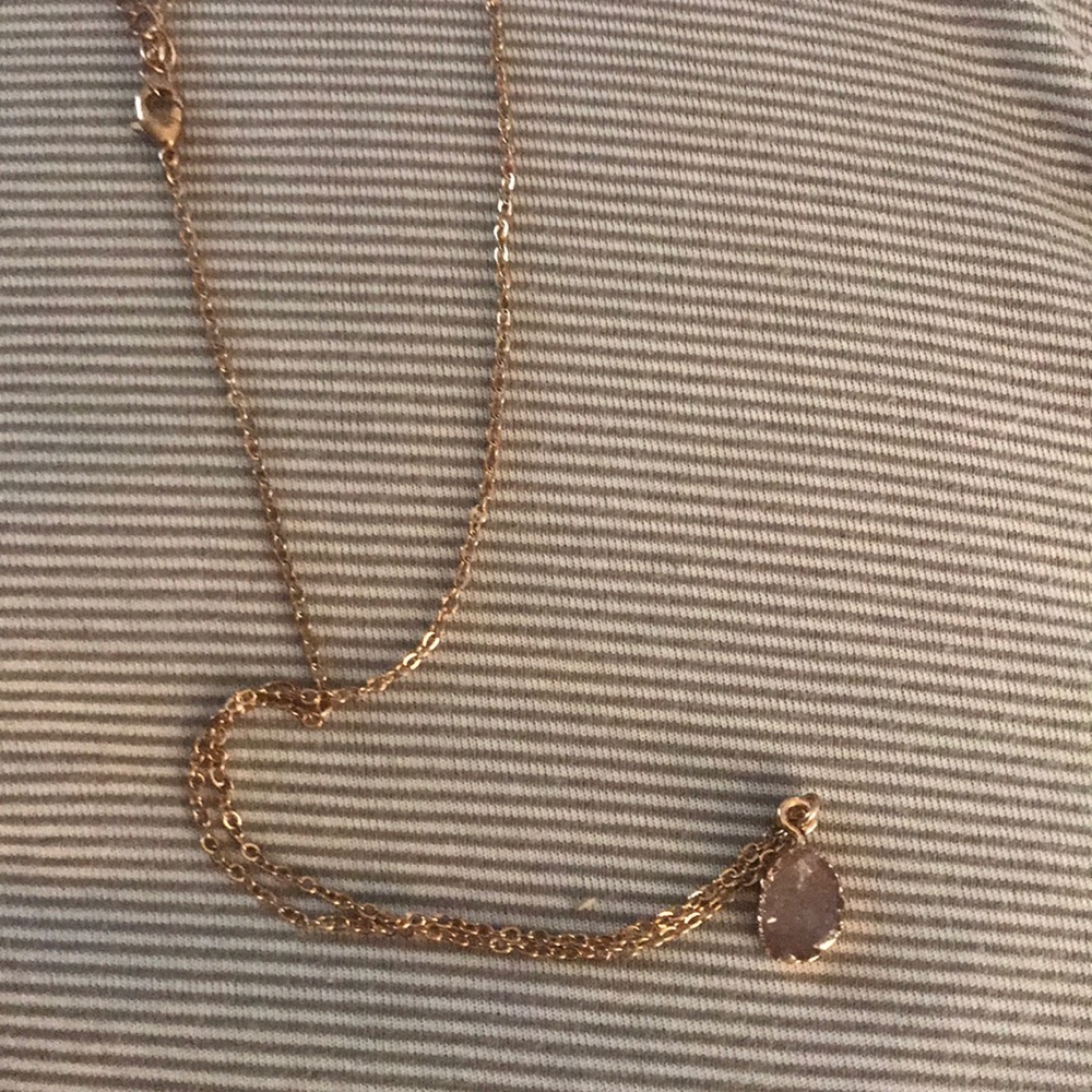 Simple gold chain necklace with pink gemstone.